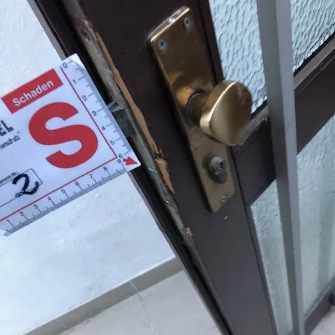 Aufgehebelter Rahmen einer braunen Aluminium-Haustür neben dem Schließblech