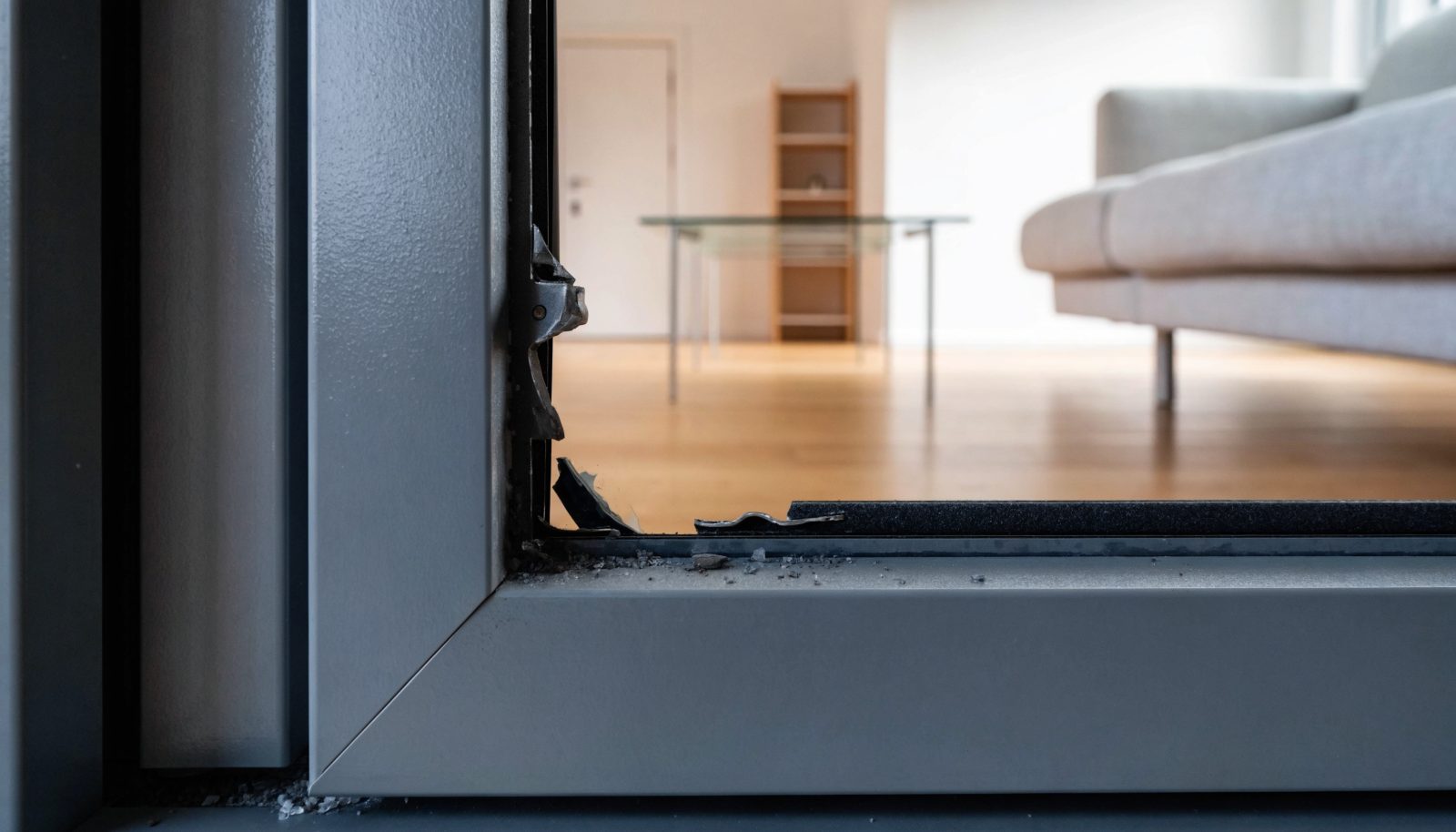 Aufgehebelter anthrazitfarbener Fensterrahmen mit Aufbruchspuren am Beschlag – Symbolbild, mit KI erstellt